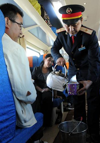 這是京藏車隊(duì)第七組乘務(wù)員王全樂在拉薩開往北京的T28次列車上為旅客送水(8月12日攝)。新華社記者 唐召明 攝