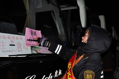 1月19日凌晨,山東青島黃島汽車總站乘務(wù)員邢云英在工業(yè)園返鄉(xiāng)員工的包車上放置指示牌。新華社發(fā)(王媛媛 攝)