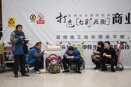 12月15日,乘客在昆明機(jī)場(chǎng)候機(jī)樓食用機(jī)場(chǎng)免費(fèi)提供的盒飯。新華社記者 張可任 攝