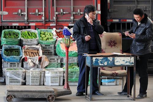 11月10日,在太原市河西農(nóng)產(chǎn)品批發(fā)市場內(nèi),一家蔬菜批發(fā)商在算賬。新華社記者 范敏達 攝