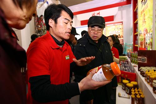 1月6日,這是安徽滁州展臺(tái)的工作人員向觀眾介紹滁州有名的純槐花蜂蜜。新華社記者 高學(xué)余 攝