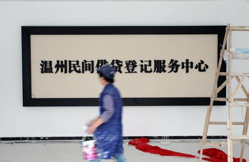 3月30日,在浙江溫州市江濱西路一座大廈內(nèi),工作人員從“溫州民間借貸登記服務(wù)中心”牌匾前走過。新華社發(fā)(蘇巧將 攝)
