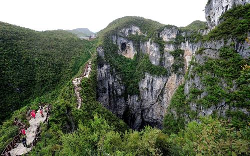游客等觀看龍缸景區(qū)的巖溶天坑(右側(cè))(4月25日攝)。新華社記者 李健 攝
