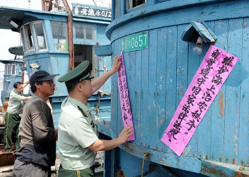 5月29日,青島邊防支隊(duì)沙子口邊防派出所民警正在轄區(qū)碼頭張貼伏季休漁期法制宣傳單。從6月1日起,黃渤海將全面進(jìn)入2012伏季休漁期。為確保休漁工作順利開展,山東邊防、漁政等部門在沿海各漁船停泊點(diǎn),向漁民宣傳伏季休漁期的法律、法規(guī)、防火、防盜等注意事項(xiàng),責(zé)任到人做到漁船入港、漁具上岸。6月1日12時(shí)至9月1日12時(shí)為北緯35度以北的渤海和黃海海域伏季休漁期。新華社記者 李紫恒 攝
