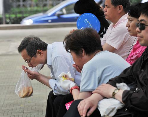6月7日,在北京西城區(qū)一處考點(diǎn)外,等待考生的家長正在吃早點(diǎn)。當(dāng)日是2012年全國高考第一天,共有約915萬名考生報(bào)名參加考試。新華社記者 李文 攝