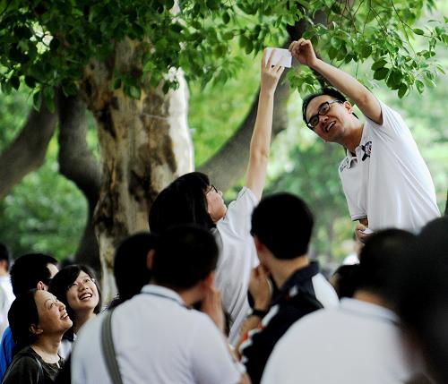 6月7日,在杭州市高級(jí)中學(xué)考點(diǎn),帶隊(duì)老師(右)將準(zhǔn)考證高高舉起,讓考生跳起來去拿,用這種方式為他們減壓放松。新華社記者 鞠煥宗 攝