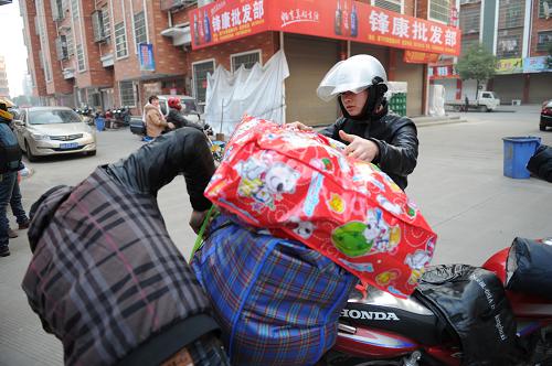 江西籍務(wù)工人員在捆綁摩托車上的行李(1月30日攝)。新華社記者 鞠煥宗 攝