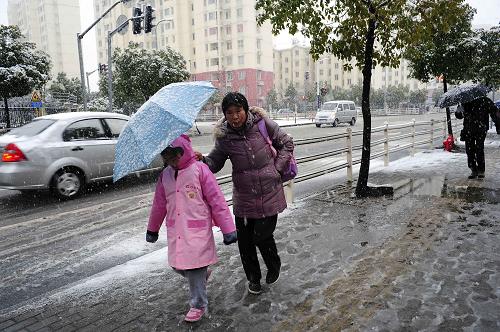 2月19日,在上海街頭,一位家長在風(fēng)雪中為孩子撐傘擋雪。新華社發(fā)(劉曉晶 攝)