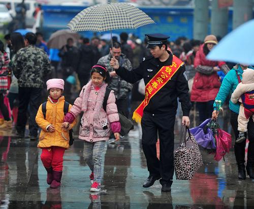 1月26日,在廣西南寧火車站廣場,一位民警在雨中為旅客撐傘。春運期間,南寧鐵路公安局在南寧火車站開展“溫暖回家路”活動。春節(jié)前后,34.07億人次踏上旅途。為了讓旅客出行順暢、舒心,各運輸部門加大運力、做好保障,并為需要幫助的旅客提供貼心的服務,成為春運大潮中一道亮麗而暖人心的風景。 新華社記者 黃孝邦 攝