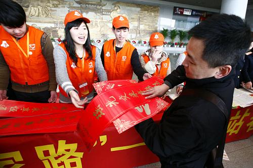 1月26日,志愿者和鐵路工作人員在江蘇南京火車站向候車旅客贈送春聯(lián)等小禮物,祝愿乘客旅途愉快,新春吉祥。 新華社發(fā)(楊謳鍇攝)