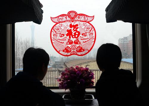 2月11日,在鄭州至哈爾濱的K926次列車上,兩位乘客在車廂內(nèi)觀賞窗外景色,窗上貼著的大紅“福”字格外醒目。新華社記者 王頌 攝