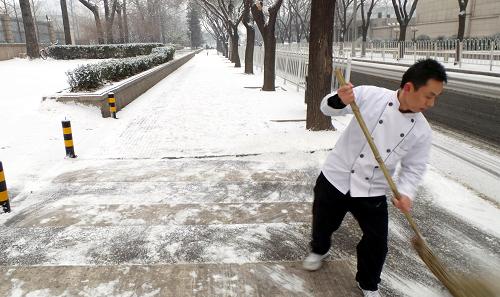 2月7日,一名飯店員工在北京街頭清掃道路積雪。當(dāng)日,北京迎來今冬首場降雪。新華社記者 李明放 攝