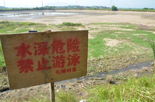 8月11日,在安徽省巢湖市槐林鎮(zhèn),一口干涸的水塘邊豎立著豐水時(shí)的警示牌。新華社發(fā)(馬豐成 攝)