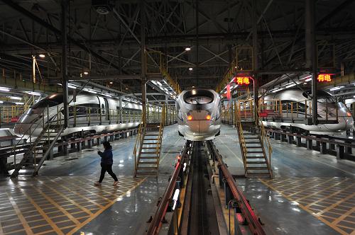 1月23日晚,一名工作人員從北京動(dòng)車段庫內(nèi)的高速動(dòng)車組旁經(jīng)過。新華社發(fā)(劉長龍 攝)