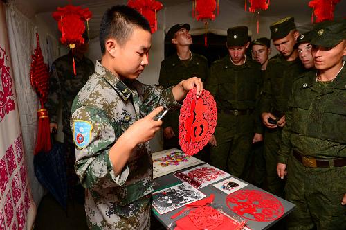 8月7日,在俄羅斯中部軍區(qū)切巴爾庫爾合同訓(xùn)練場,中方戰(zhàn)士現(xiàn)場為俄軍官兵演示剪紙藝術(shù)。當(dāng)天下午,參加“和平使命—2013”中俄聯(lián)合反恐軍事演習(xí)的俄方部分參演官兵參觀了中國傳統(tǒng)文化體驗(yàn)館。體驗(yàn)館設(shè)在切巴爾庫爾合同訓(xùn)練場一處野戰(zhàn)兵營帳篷內(nèi),內(nèi)有中國茶道、國畫、京劇臉譜、蛋雕、剪紙等八個文化展區(qū),令俄方參演官兵大開眼界。新華社發(fā)(譚長俊攝)
