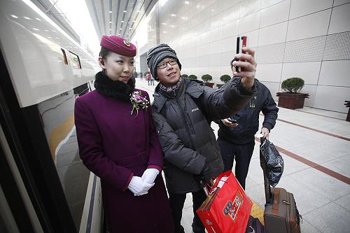 12月26日,在北京西站,乘坐前往廣州的G801次高鐵的旅客和服務員合影。新華社記者 王申 攝