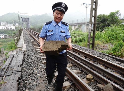7月16日,一名護(hù)路民警在襄渝鐵路四川省達(dá)州市木頭段清除在暴風(fēng)雨中滑落到鐵道上的石頭。7月16日凌晨,四川省達(dá)州市再次出現(xiàn)暴雨天氣,多個地方不同程度出現(xiàn)滑坡、道路塌方等險情。達(dá)州市鐵路部門針對近期多輪強(qiáng)降雨所引發(fā)的水毀路、滑坡、飛石等襲擾,從7月中旬起組織300余名鐵路民警及護(hù)路聯(lián)防隊員,分布到所轄逾310公里的襄渝鐵路、達(dá)成鐵路、達(dá)萬鐵路干線,分段包線對水毀后修復(fù)路段、飛石和滑坡等地質(zhì)災(zāi)害易發(fā)區(qū)域鐵道設(shè)施進(jìn)行重點巡查監(jiān)控,確保暑運期間每日360多列客貨列車順利過境。新華社發(fā)(鄧良奎 攝)