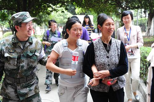 4月25日,楊美江(左二)在媽媽和軍醫(yī)的陪同下返回校園。4月25日,四川雅安蘆山中學(xué)高三女孩楊美江終于穿上了第三軍醫(yī)大學(xué)西南醫(yī)院為她量身訂制的胸腰外部固定支具,離開(kāi)了病床走出了帳篷。突如其來(lái)的地震讓正在備戰(zhàn)高考的楊美江受傷,胸椎2個(gè)椎體壓縮性骨折,不能正常坐立,需要臥床靜養(yǎng)三個(gè)月,這對(duì)于高考在即的楊美江來(lái)說(shuō)無(wú)疑是晴天霹靂。4月23日,焦急萬(wàn)分的她來(lái)到第三軍醫(yī)大學(xué)醫(yī)療隊(duì)求救,當(dāng)天上午10時(shí)30分,醫(yī)療隊(duì)與第三軍醫(yī)大學(xué)西南醫(yī)院接通了遠(yuǎn)程會(huì)診的視頻,遠(yuǎn)在重慶的康復(fù)科、骨科專家與醫(yī)療隊(duì)急救專家一起幫楊美江研究既不影響學(xué)習(xí)又能參加高考的治療方案,加班加點(diǎn)為她量身定做一副胸、腰部外固定支具,她戴上后就可以正常坐著參加學(xué)習(xí)。兩天后,西南醫(yī)院專程從千里之外將做好的支具送到蘆山災(zāi)區(qū),圓了楊美江的高考?jí)?。新華社發(fā)(王中委 攝)