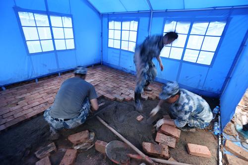 5月9日,成都軍區(qū)空軍官兵在青龍場村集中安置點為積水帳篷鋪紅磚。新華社發(fā)(劉應(yīng)華 攝)