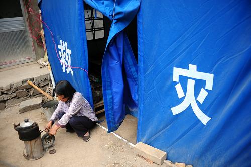 8月27日,在甘肅省岷縣茶埠鎮(zhèn)大竜村,一位受災(zāi)村民在自家棉帳篷外生火燒水。新華社記者 張錳 攝