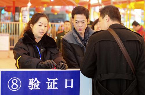 2月15日,在江西九江火車站進口處,南昌鐵路局九江橋工段的工作人員在為旅客檢票。新華社發(fā)(胡國林 攝)