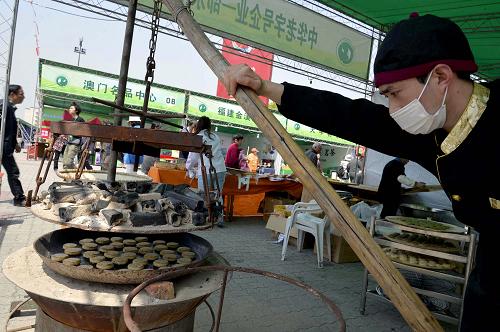 4月12日,一家參展企業(yè)在“清河坊民間茶會(huì)”上烘烤傳統(tǒng)名點(diǎn)茶餅。新華社發(fā)(龍巍 攝)