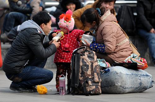 2月15日,一位小朋友和父母在鄭州火車站東廣場候車。新華社記者 李博 攝