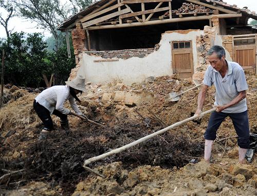 6月12日,江西寧都縣黃陂鎮(zhèn)荷樹村農(nóng)民正在倒塌的房屋前清理物品。新華社記者 周科 攝