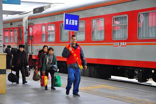 2月15日,一名青年志愿者在成都火車站舉牌引導重點旅客乘車。新華社發(fā)(胡志強 攝)