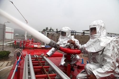 7月8日,在山東威海威洋石油公司油庫,消防隊員利用高壓水炮對油罐的“高空著火點”進(jìn)行降溫壓制滅火。新華社發(fā)(于啟波 攝)