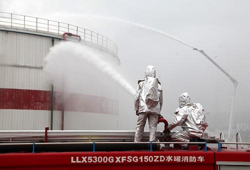 7月8日,在山東威海威洋石油公司油庫,消防隊員利用高壓水炮對油罐的“高空著火點”進(jìn)行降溫壓制滅火。新華社發(fā)(于啟波 攝)