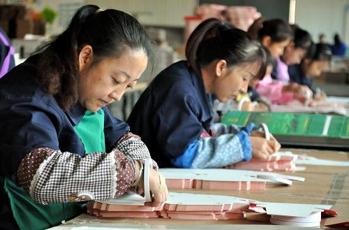 10月24日,蘭州非公企業(yè)華宇彩印包裝有限公司的工人在手工粘貼印刷品。新華社記者 郭剛 攝