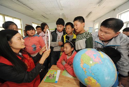 4月21日,在山東省昌樂縣西尖小學,志愿者向小學生們講解節(jié)能燈的工作原理。新華社記者李曉果攝