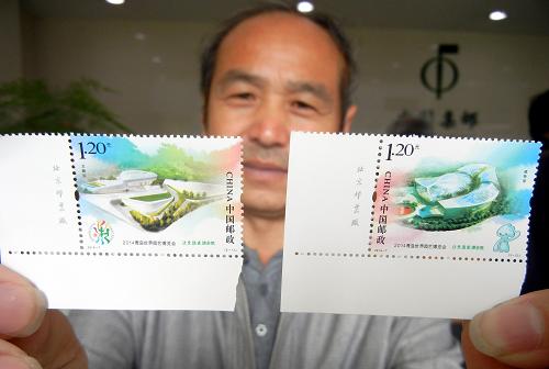 4月25日,一名集郵愛好者在蘇州郵政局展示剛購買的《2014青島世界園藝博覽會》紀念郵票。新華社發(fā)(王建康 攝)