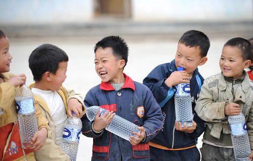 3月30日,天峨縣坡結鄉(xiāng)龍鳳村完全小學的同學們在品嘗剛剛領取的純凈水。新華社記者 黃孝邦 攝