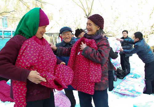 1月25日,在山東省青州市廟子鎮(zhèn)里單家峪村,三名空巢老人在身上比量剛領(lǐng)到的新棉衣。新華社發(fā)(孫樹寶 攝)