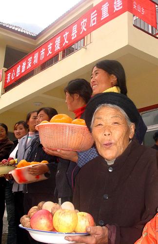 11月11日,在甘肅隴南災(zāi)區(qū)第一批完成重建的重建村之一文縣尖山鄉(xiāng)宋家壩村,群眾給援建者送上蘋果、核桃等土特產(chǎn),以表感激之情。 新華社記者 屠國璽 攝