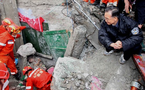 5月13日,溫家寶總理在四川都江堰市新建小學(xué)察看災(zāi)情時,看見救援人員正在教學(xué)樓廢墟里搶救一名被困的小學(xué)生。溫家寶蹲坐在廢墟上對著孩子說,我是溫家寶爺爺,孩子們一定要挺住,一定會得救! 新華社記者 姚大偉 攝