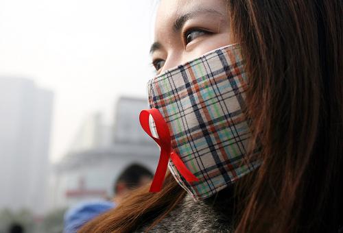 12月1日,在防治艾滋病主題宣傳活動上,一名女孩將紅絲帶粘在口罩上。當日,上海市閘北區(qū)疾病預防控制中心在上海火車站廣場開展以“遏制艾滋,履行承諾”為主題的防治艾滋病宣傳活動。新華社發(fā)
