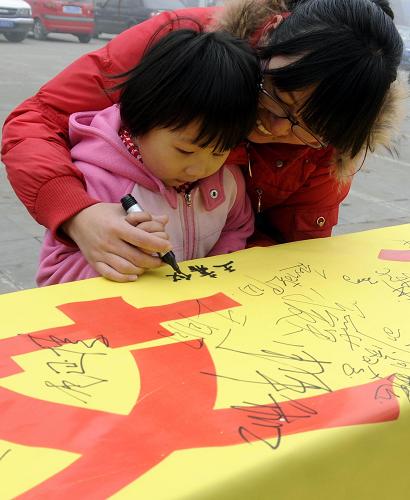 12月1日,一位母親帶著孩子在“遏制艾滋 履行承諾”的橫幅上簽名。當日,河北省邢臺市疾病預防控制中心工作人員走上街頭,開展預防艾滋病宣傳活動,普及艾滋病防治知識。新華社發(fā)(黃濤 攝)