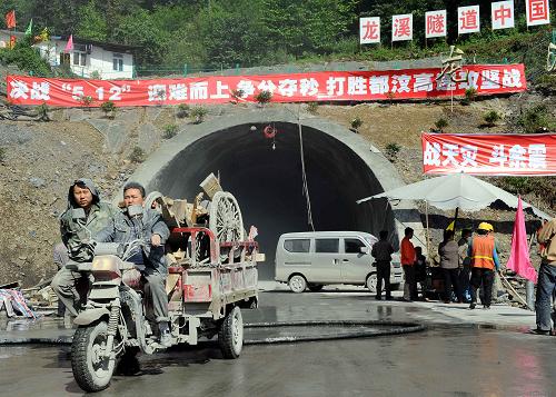 5月3日,在都汶公路龍溪隧道洞口前,施工人員在進(jìn)行工程收尾工作。據(jù)了解,都(江堰)汶(川)公路關(guān)鍵控制性工程龍溪隧道主體工程已全面完工,目前正在進(jìn)行最后的路面施工和收尾配套階段。被稱(chēng)為災(zāi)區(qū)“生命線”的都汶公路大通道將按期在5月12日汶川地震一周年之際正式建成通車(chē)。都汶公路全長(zhǎng)82.54公里,其中,都江堰至映秀段的25.95公里為雙向四車(chē)道的高速公路,映秀至汶川段的56.59公里為二級(jí)公路。 新華社記者 陳凱 攝