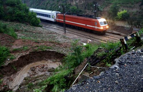 7月24日,列車從恢復(fù)運行的隴海鐵路935+050公里段通過。記者7月24日早晨從發(fā)生塌方事故的隴海鐵路搶修現(xiàn)場了解到,因強降雨導(dǎo)致的隴海鐵路中斷區(qū)段已于當(dāng)日3時30分左右恢復(fù)運行。7月23日18時30分許,隴海鐵路太要至潼關(guān)段遭受今年最強降雨襲擊,致使區(qū)段內(nèi)多處地段塌方,泥石流和傾倒的樹木阻斷了鐵路線路,隴海鐵路運行被迫中斷,影響多列旅客列車運行。 新華社發(fā)(劉瀟 攝)
