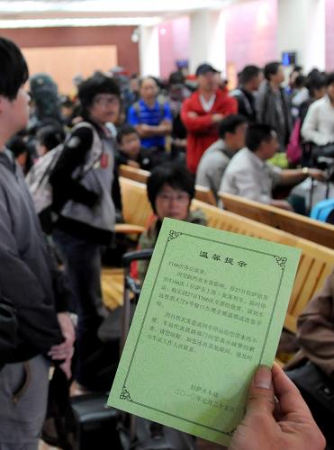7月26日,一名旅客在候車室閱讀火車站提供的晚點(diǎn)列車信息提示卡。 新華社記者 文濤 攝
