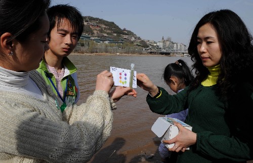 3月22日,在蘭州市的黃河岸邊,來自西北師范大學(xué)的志愿者現(xiàn)場(chǎng)展示黃河水質(zhì)檢驗(yàn)結(jié)果。