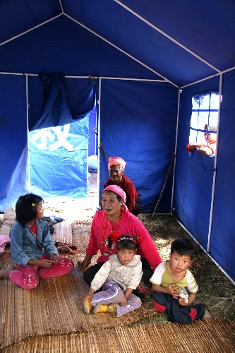3月23日,盈江縣銅壁關(guān)鄉(xiāng)孔木單景坡山寨岳堆若老人(二排右一)一家住進(jìn)救災(zāi)帳篷里。 新華社記者 陳海寧 攝