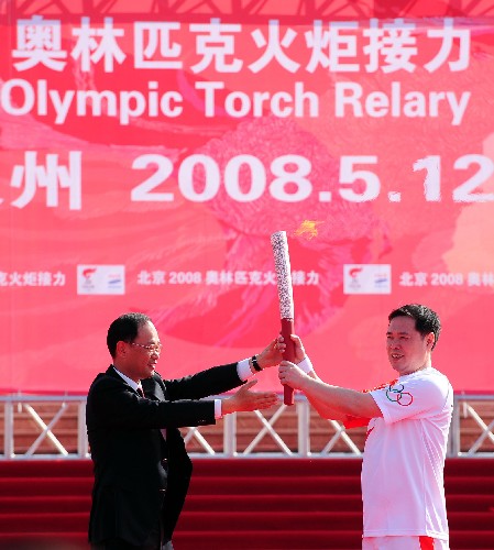 5月12日,泉州市委書記徐鋼(左)在起跑儀式上,將點燃的火炬交給第一棒火炬手王家聲。 新華社記者 姜克紅 攝