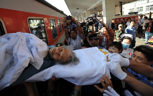 5月28日,在太原市火車站,87歲的魯桂珍被志愿者和醫(yī)護人員從列車上小心地抬下來。當日,汶川地震災區(qū)的98名傷員從四川綿陽乘專列抵達太原,太原市4所接收傷員的醫(yī)院醫(yī)護人員迅速對傷員進行救治和護理。