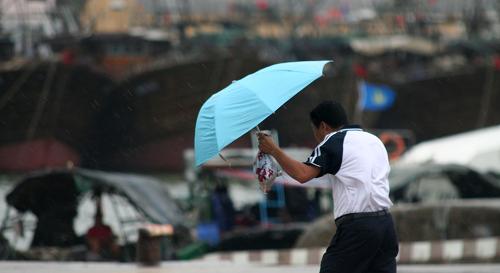 8月5日,海口市民撐著雨傘通過人行天橋。新華社記者 趙穎全 攝