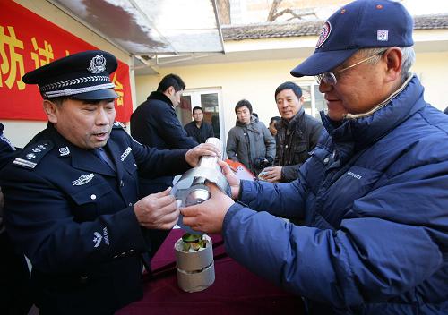 12月3日,民警在社區(qū)內(nèi)為居民講解煙筒防風(fēng)帽的安裝使用方法。新華社記者 袁滿 攝