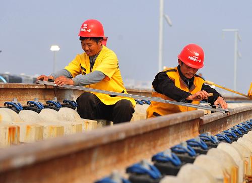 10月16日,負(fù)責(zé)石武客專湖北段施工的中鐵十一局工人正在進(jìn)行軌道定位。石武客運(yùn)專線是京廣客運(yùn)專線的一部分,北接剛剛開工建設(shè)的京石客運(yùn)專線,南連武廣客運(yùn)專線,三段客運(yùn)專線相連,構(gòu)成貫穿我國南北的高速鐵路大動脈。石武客專正線長度840公里,設(shè)計最高運(yùn)行時速將達(dá)350公里。由于高鐵施工精度要求極高,而秋季的氣溫適中,正是施工的黃金季節(jié),目前各建設(shè)單位正加緊施工建設(shè)。